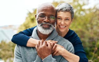 older couple hugging and smiling with teeth